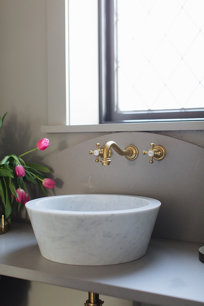 White Marble bathroom vessel sink with grey quartz countertop and brass wall mount faucet all sources on Home Bunch #bathroom #marblesink #vesselsink #wallmountfaucet